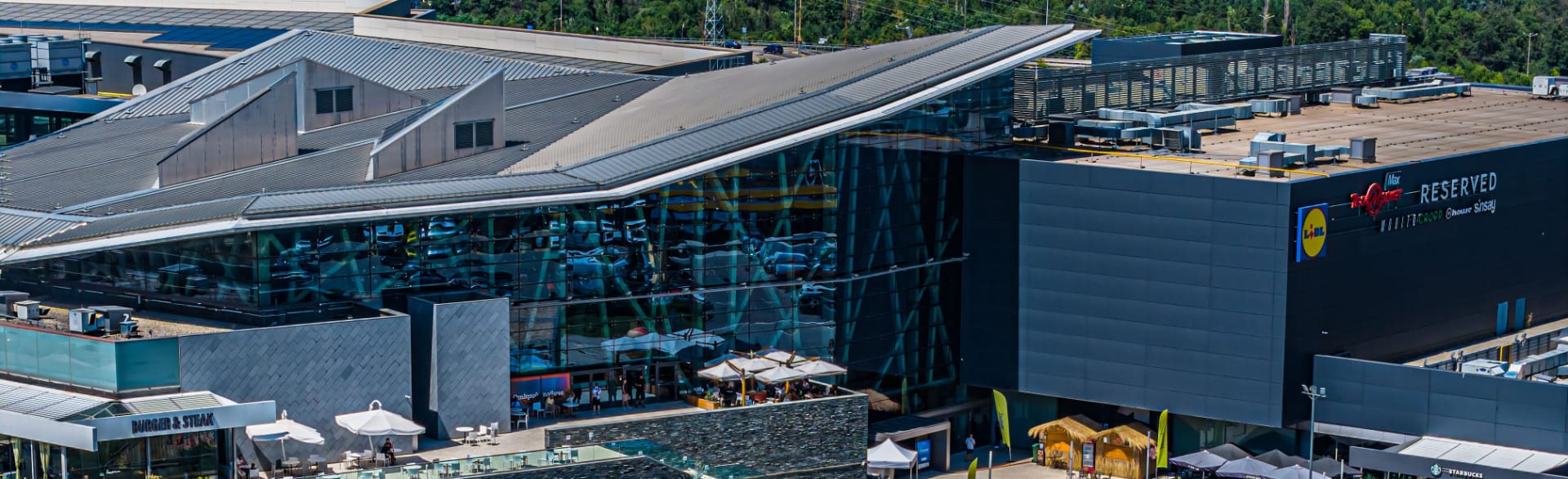 Стъклената фасада на атриума на Sofia Ring Mall отвън, с терасите пред главния вход