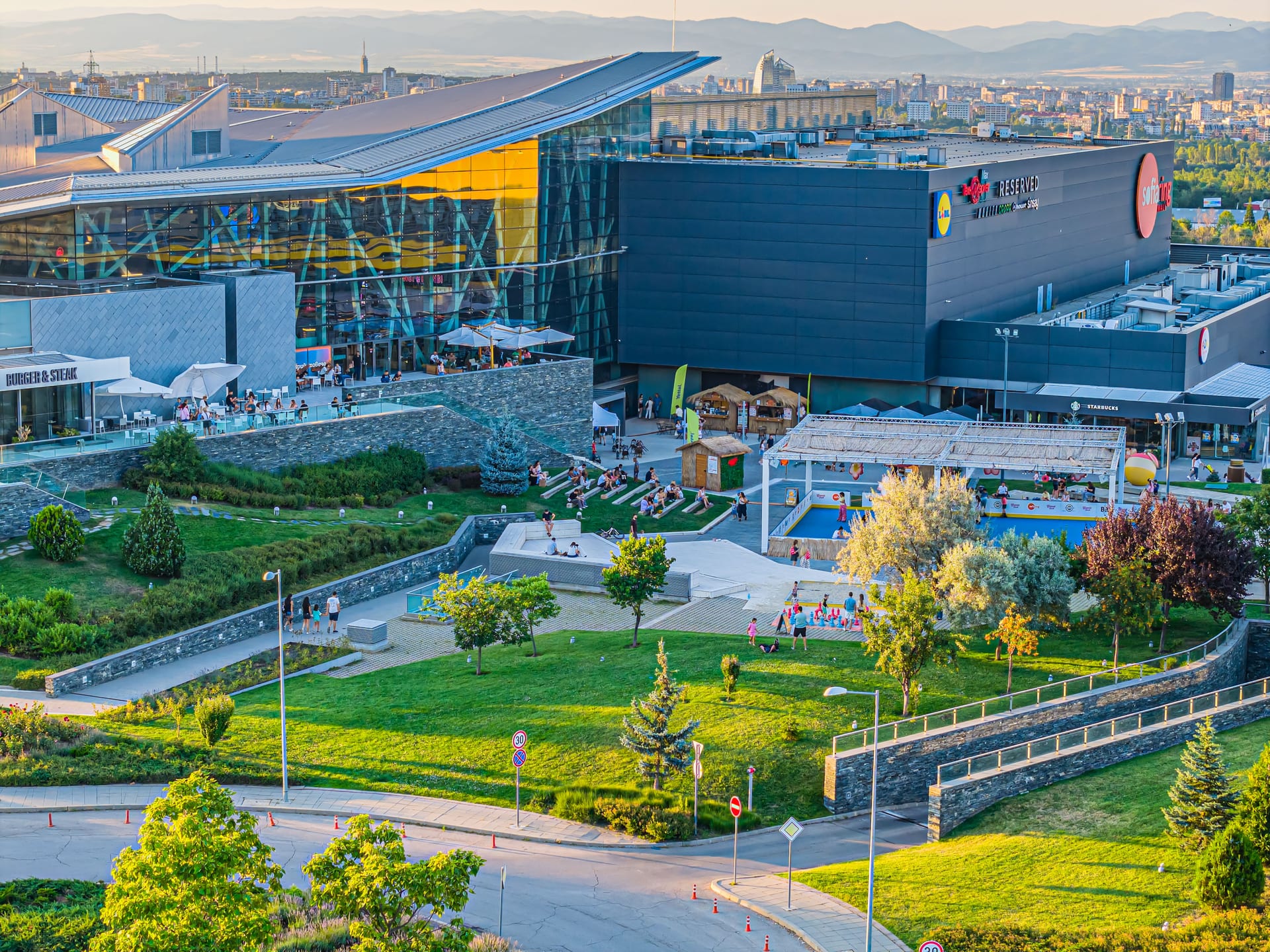 Площадът пред главния вход — стъклената фасада и зелените площи на Sofia Ring Mall